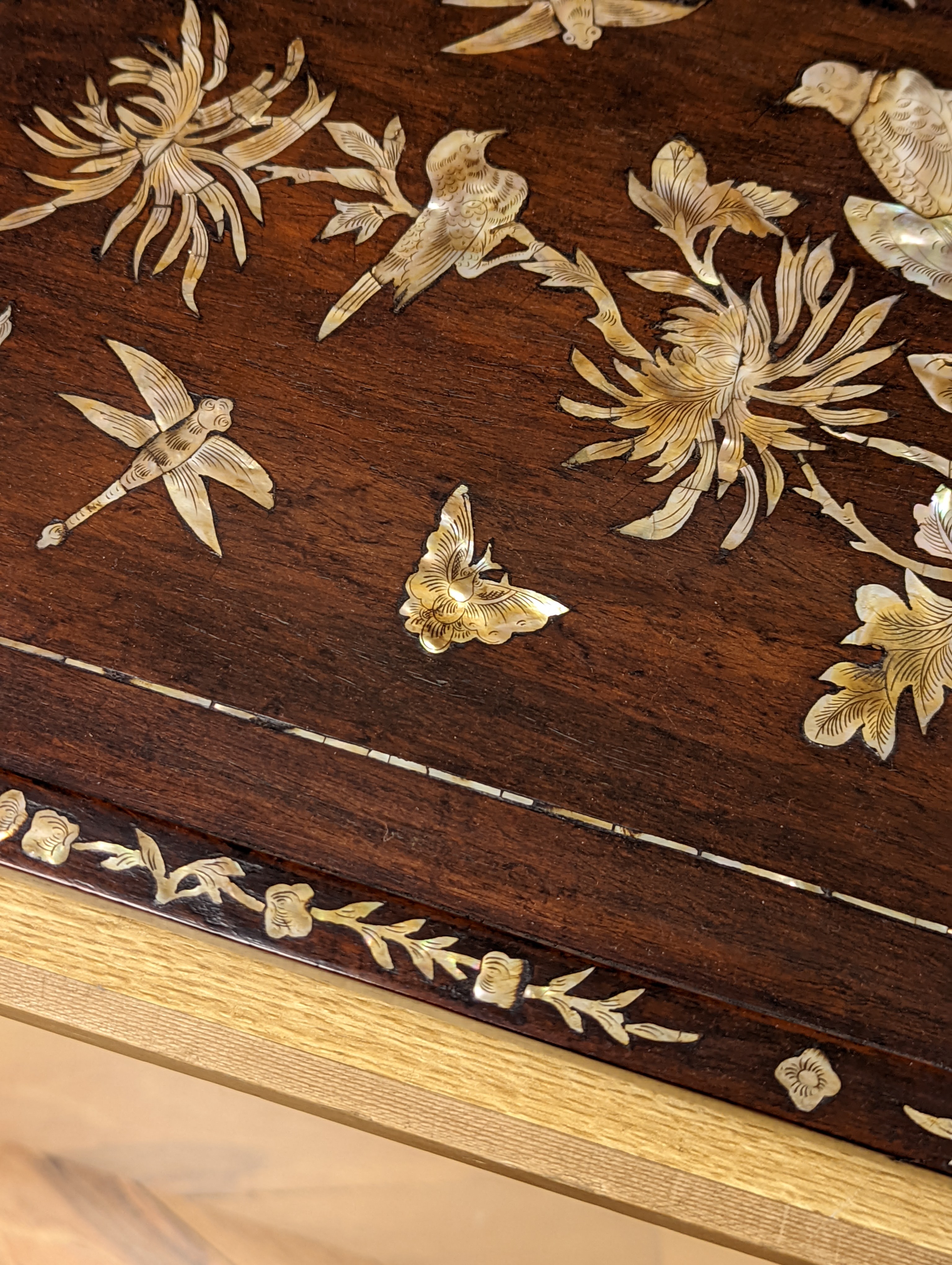 Two Chinese mother of pearl inlaid hongmu trays, the rectangular example with birds and insects amid flowers and the smaller oval example with a pavilion in a landscape within floral sprays 55x34cm